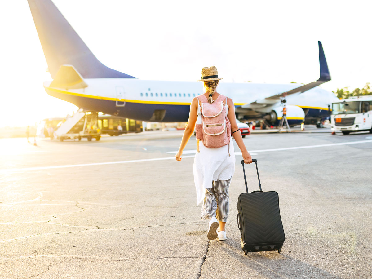 Traveler rolling suitcase across tarmac to board airplane