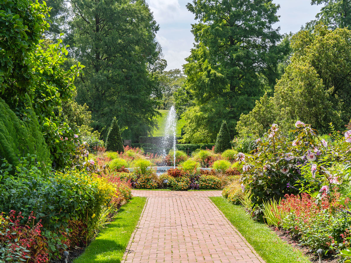 Flower-lined brick pathway leading to fountain at Longwood Gardens in Pennsylvania