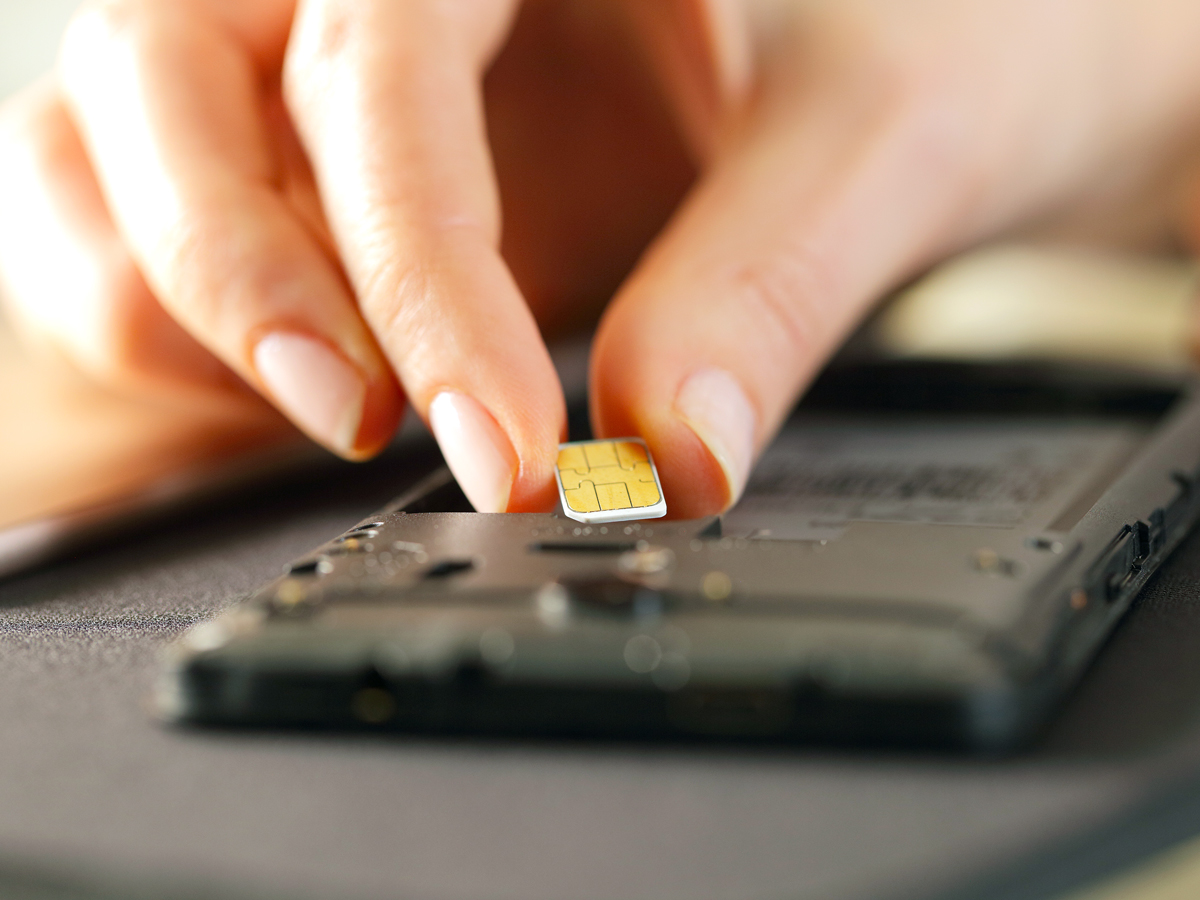 Person inserting physical SIM card in cellphone