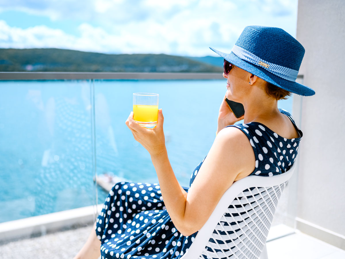 Cruise passenger sitting on balcony with drink in hand
