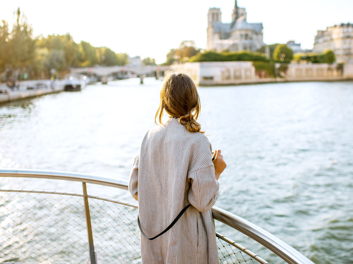 Person standing on deck of cruise ship overlooking river 