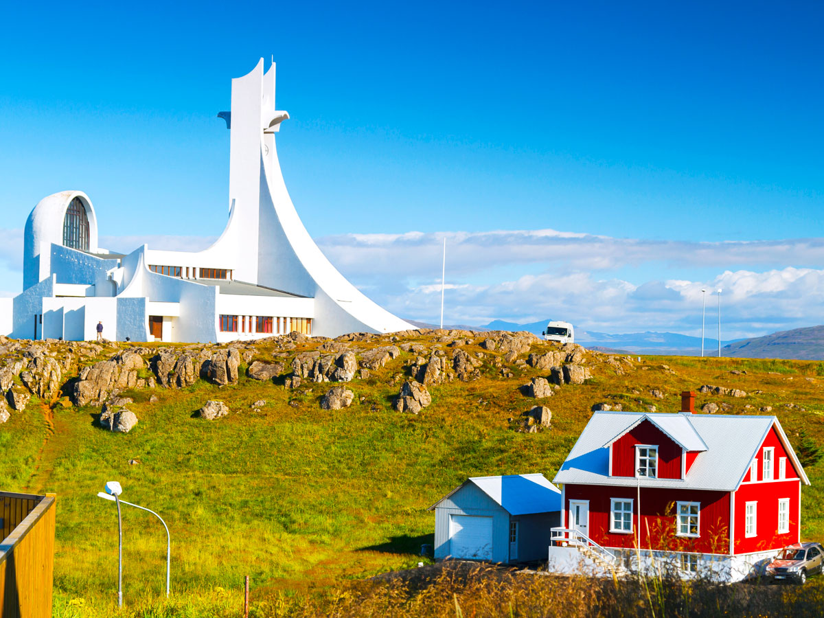 Bright red home in front of Iceland's Stykkishólmskirkja Church