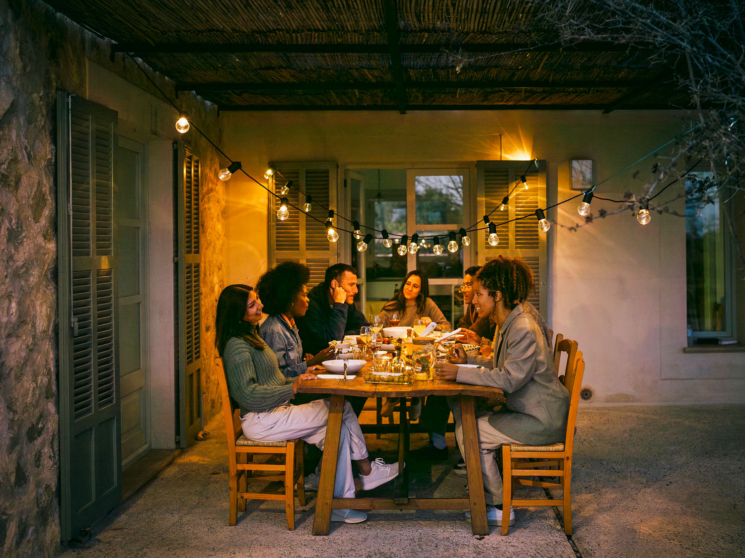 Friends gathered for alfresco dinner under hanging lights