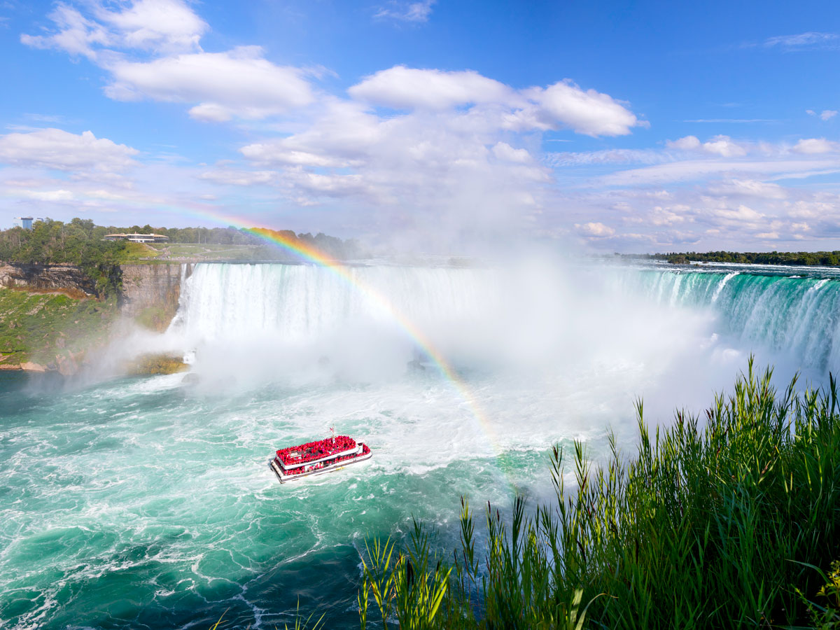 Rainbow over sightseeing boat by Niagara Falls