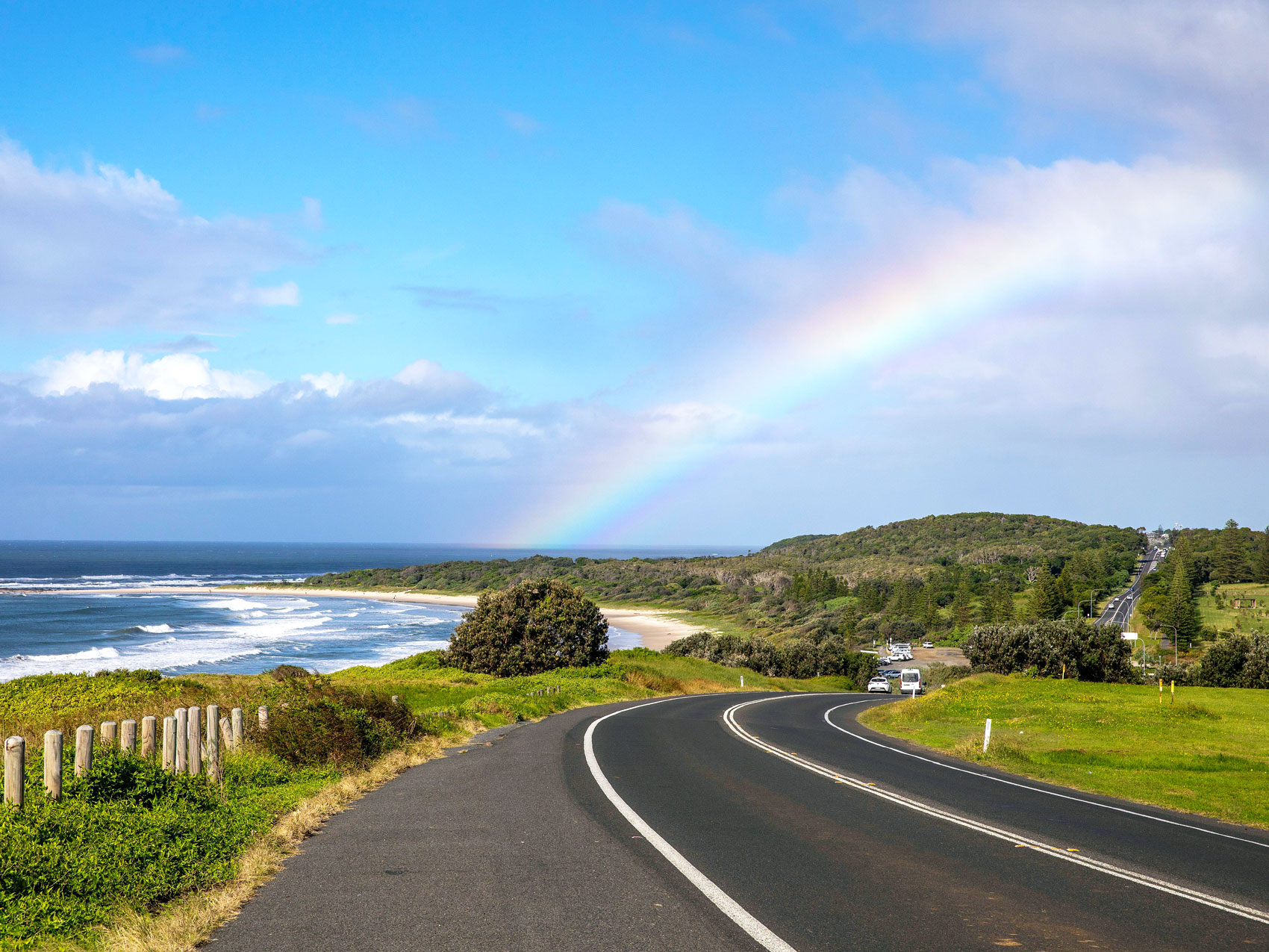 Road winding underneath rainbow on Australia's Rainbow Coast