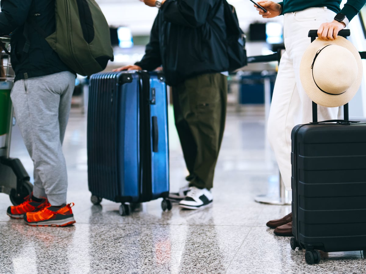 Travelers waiting in line with luggage at airport