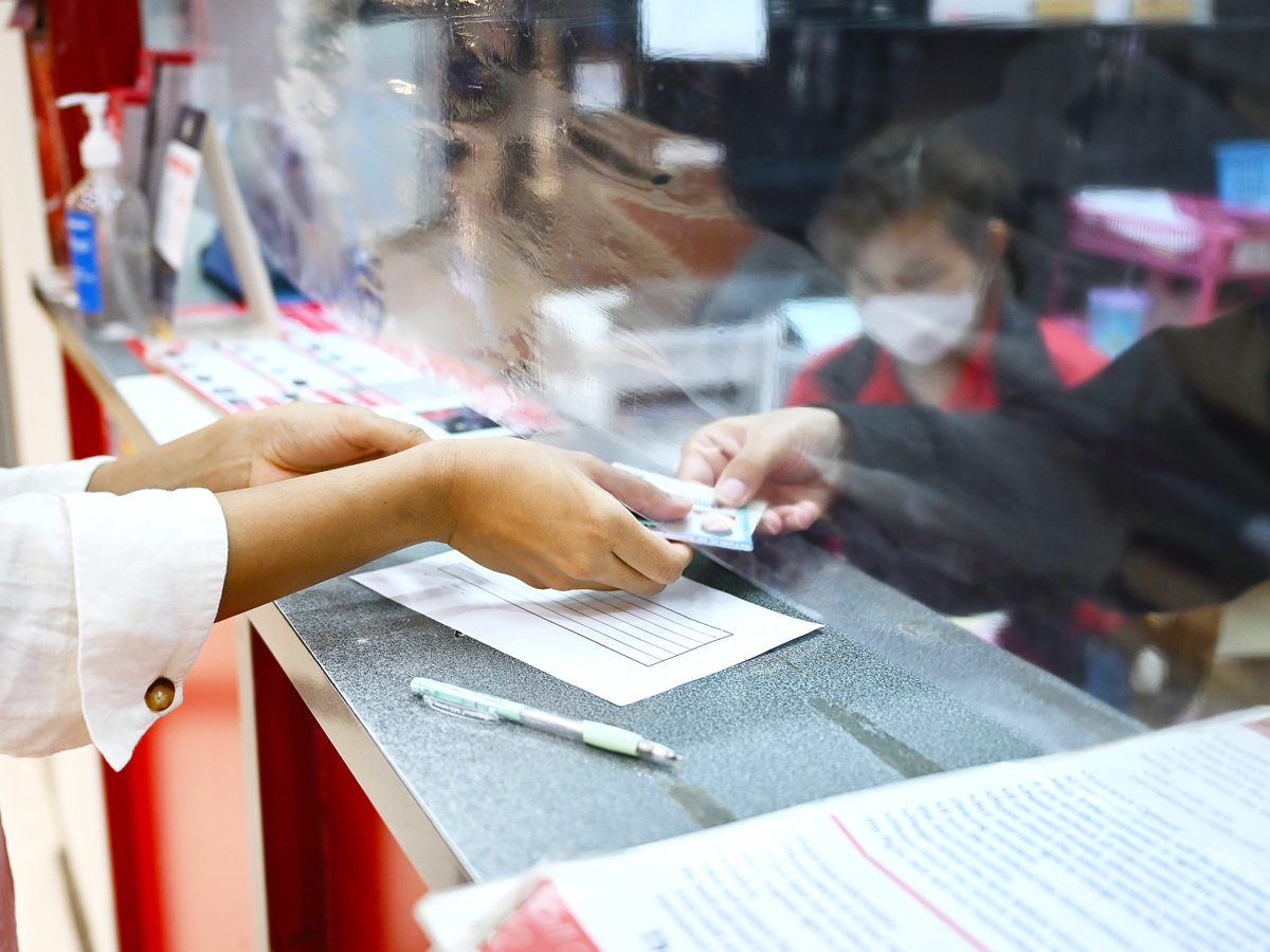 Person handing driver's license to employee behind desk