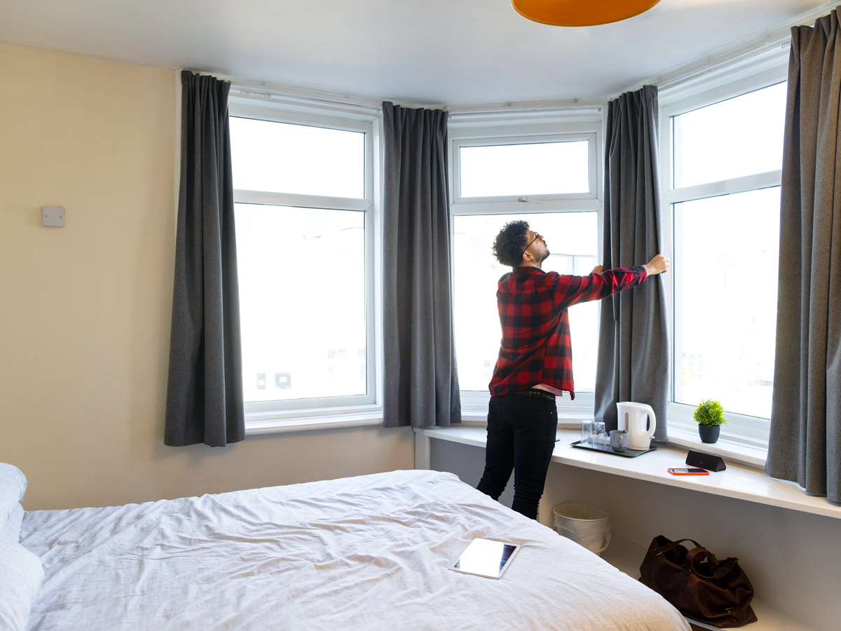 Person opening hotel room curtains