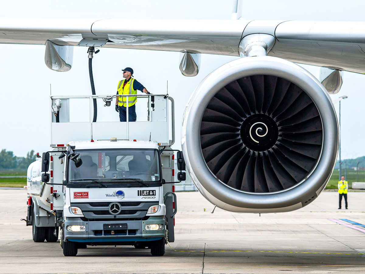 Employee fueling jet parked at airport gate
