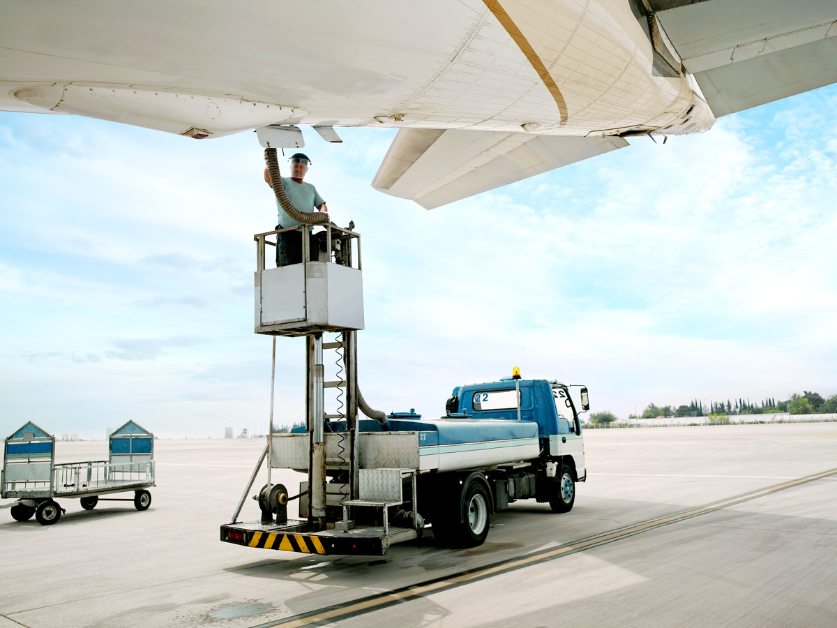 Airport employee on truck connecting vacuum pipe to aircraft