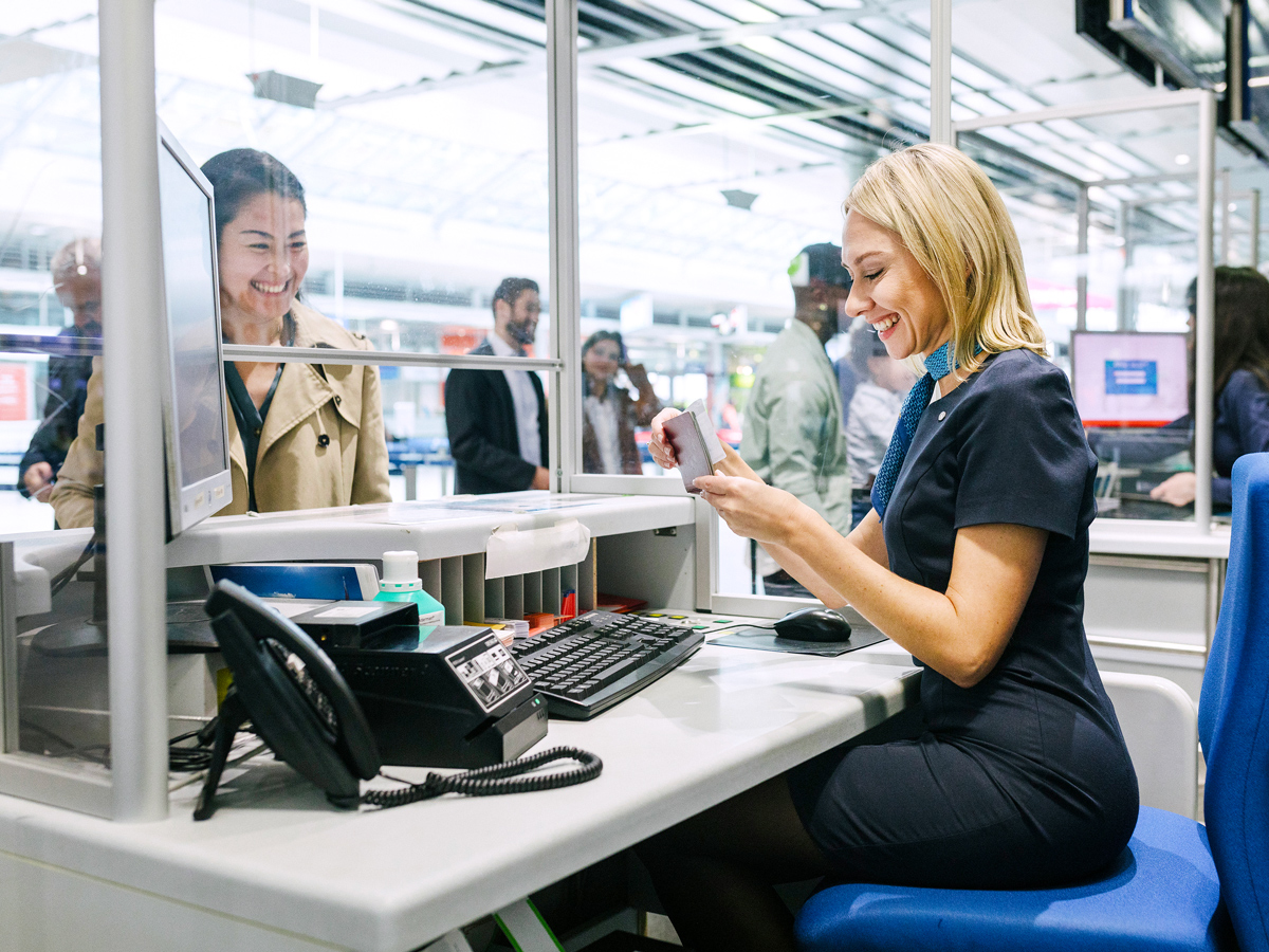 Airport check-in agent reviewing passenger's passport