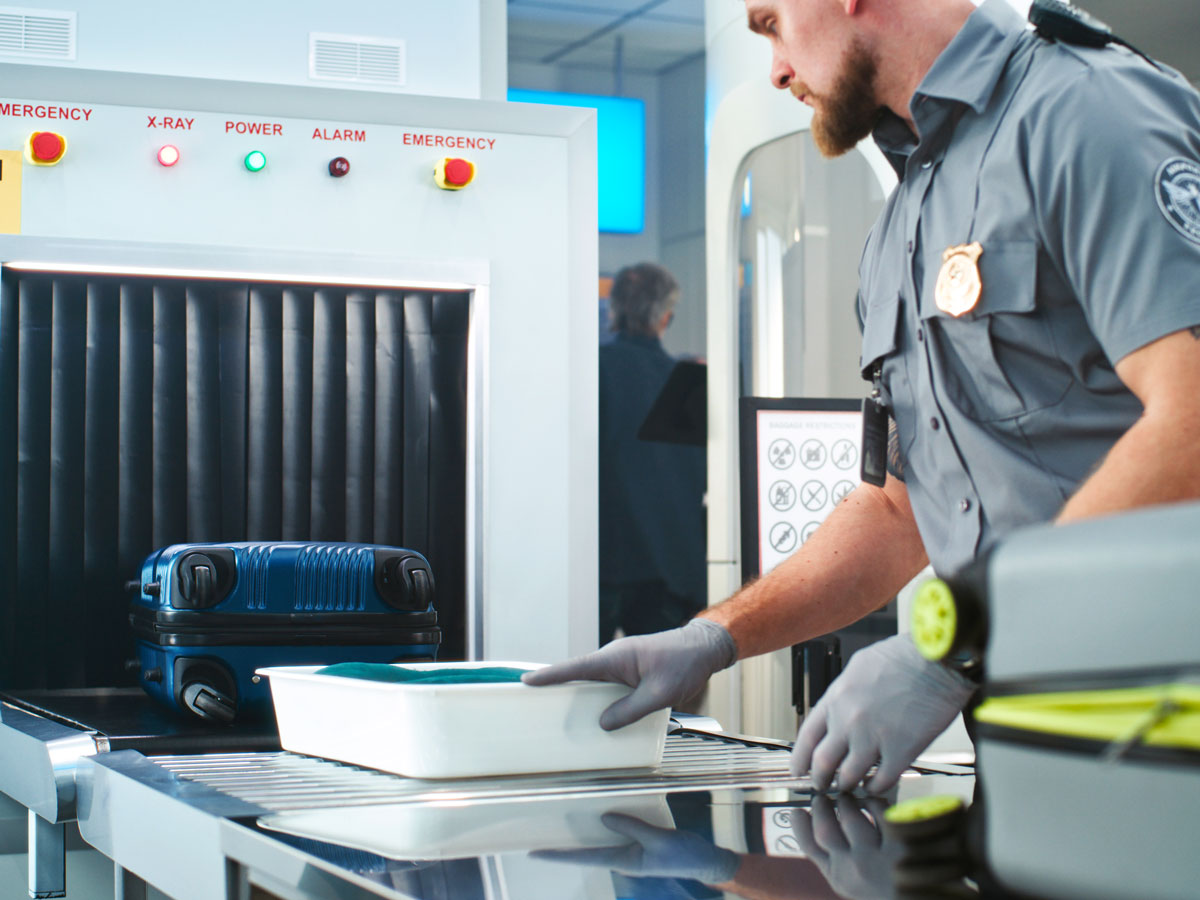 Security officer placing bin on X-ray belt at airport security checkpoint