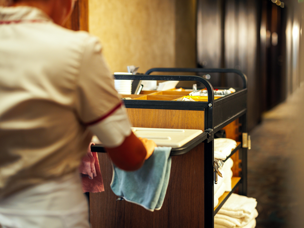 Housekeeping staff pushing cart down hotel hallway