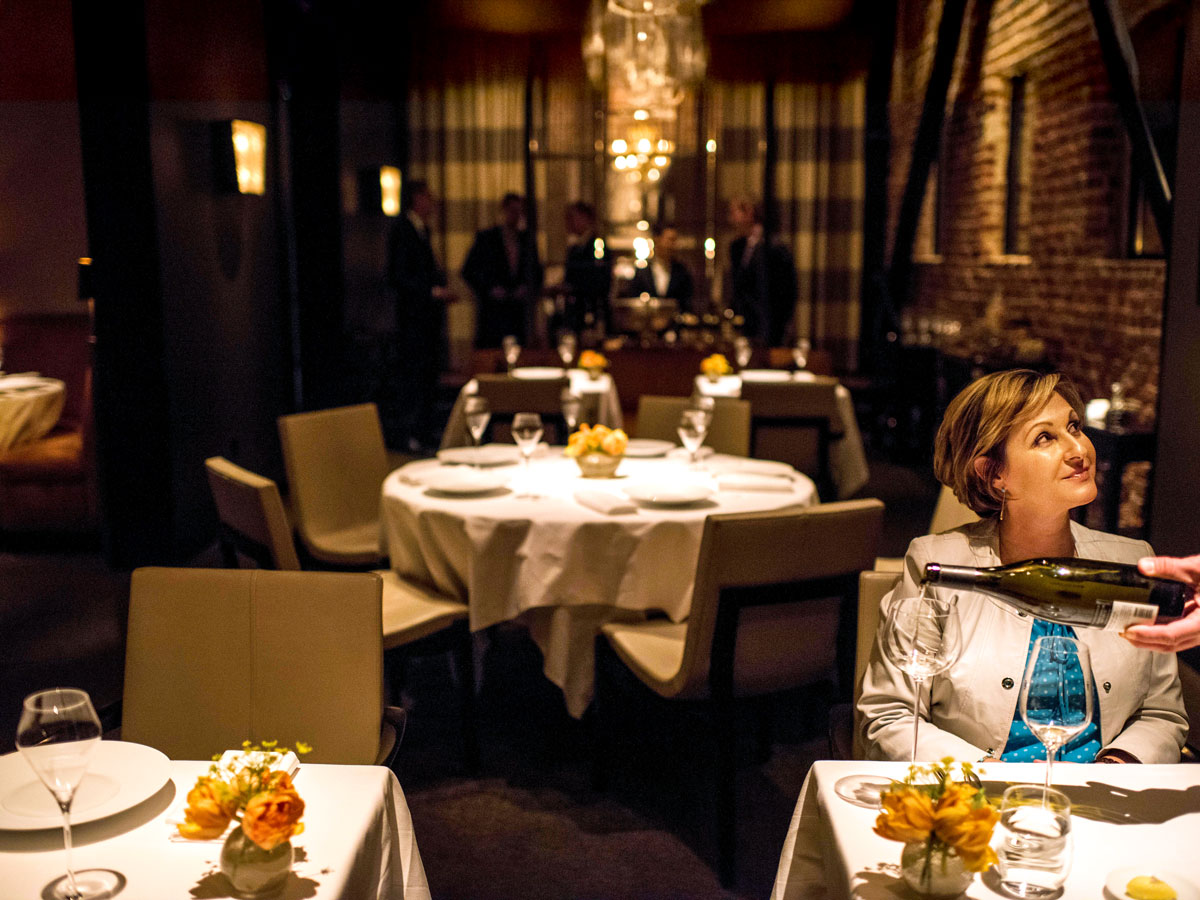 Waiter pouring wine for diner at Quince restaurant in San Francisco, California