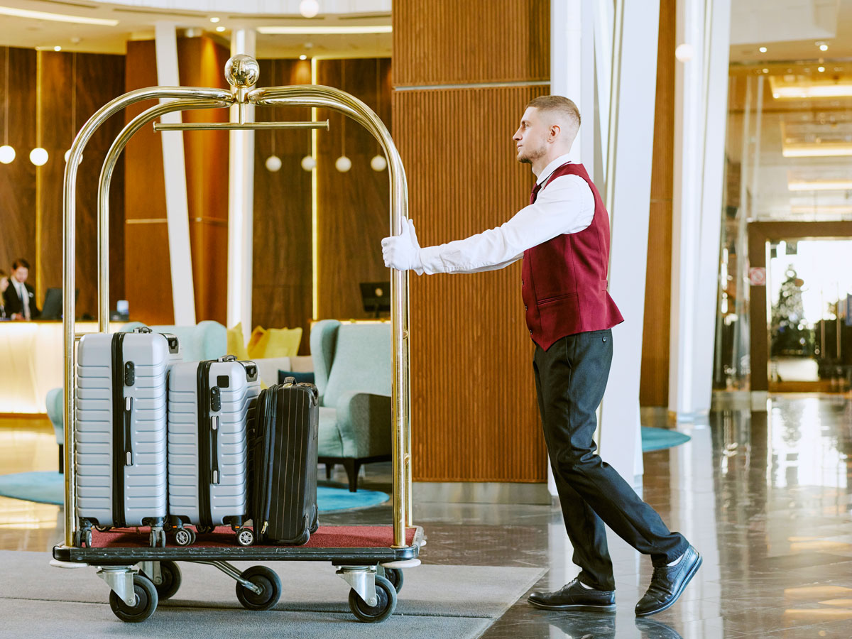 Hotel bellhop pushing trolley with luggage