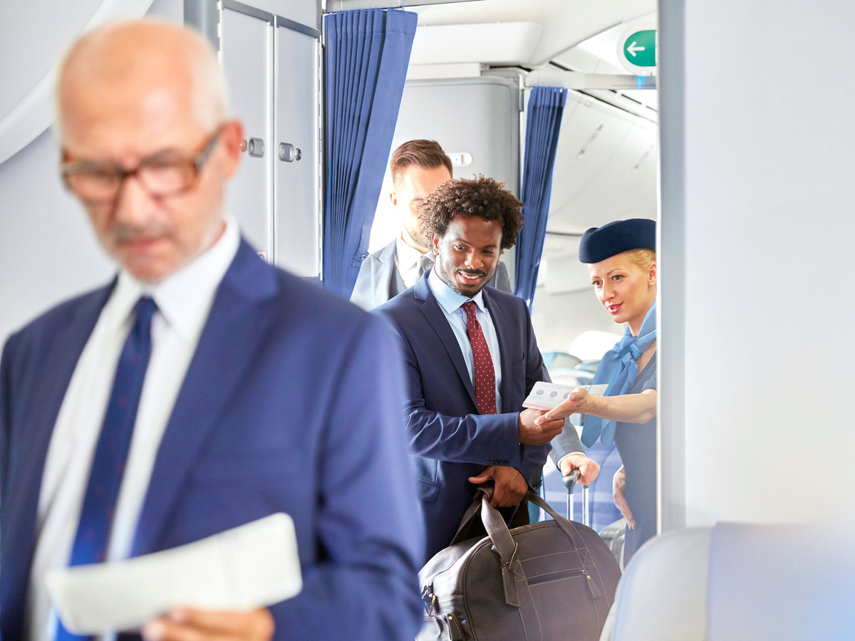 Flight attendant greeting passengers boarding aircraft