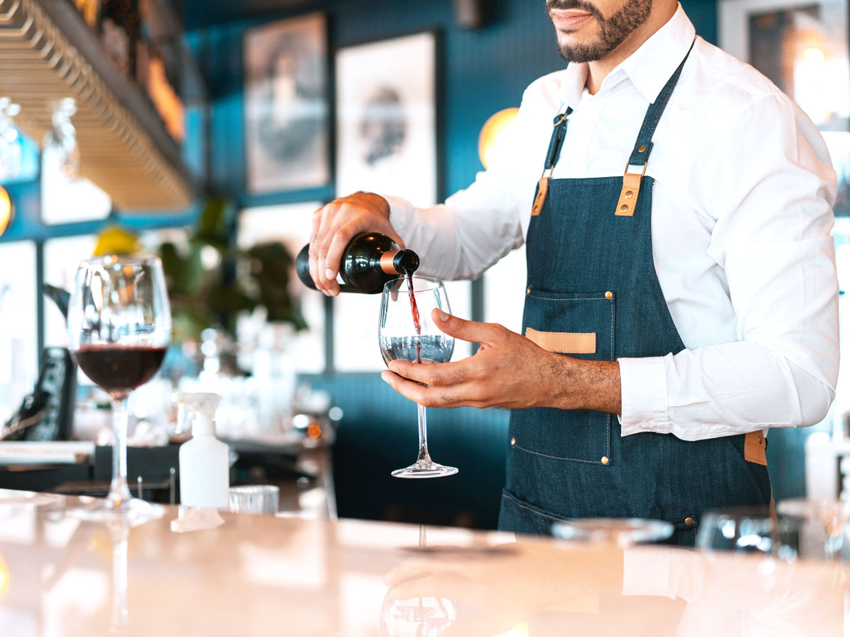 Bartender pouring glass of wine at bar