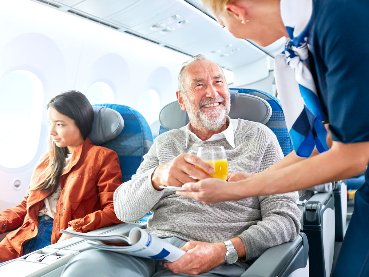 Flight attendant serving drink to passenger