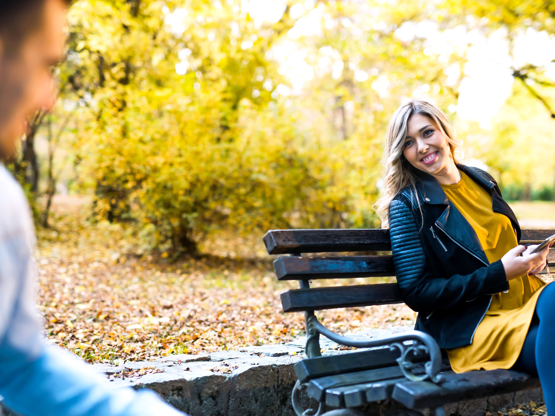 Woman sitting on bench smiling at another person