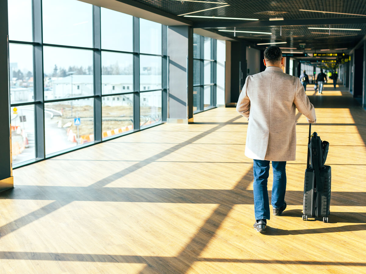 Passenger walking through airport terminal with suitcase