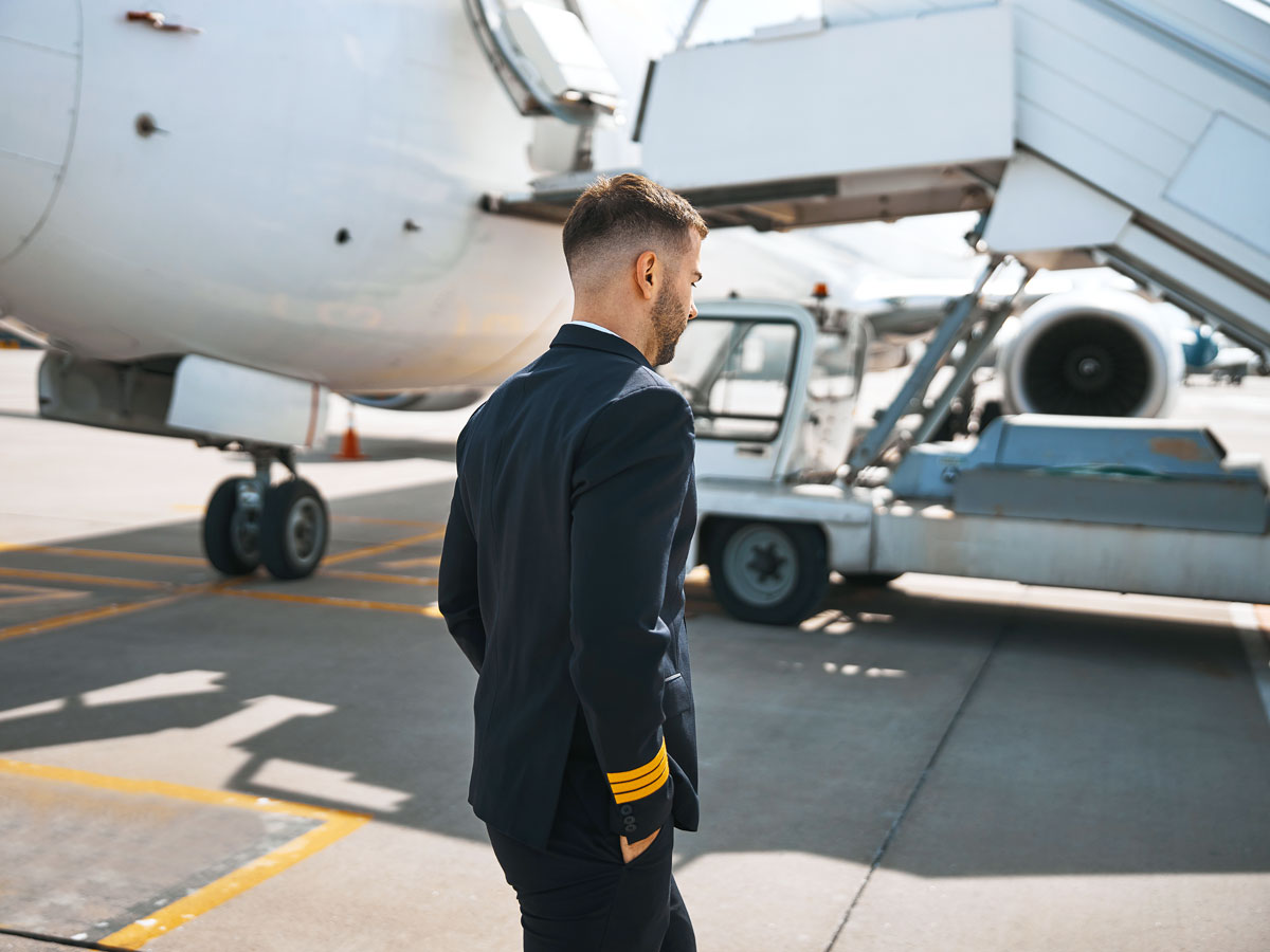 Pilot conducting walk-around of aircraft parked at gate