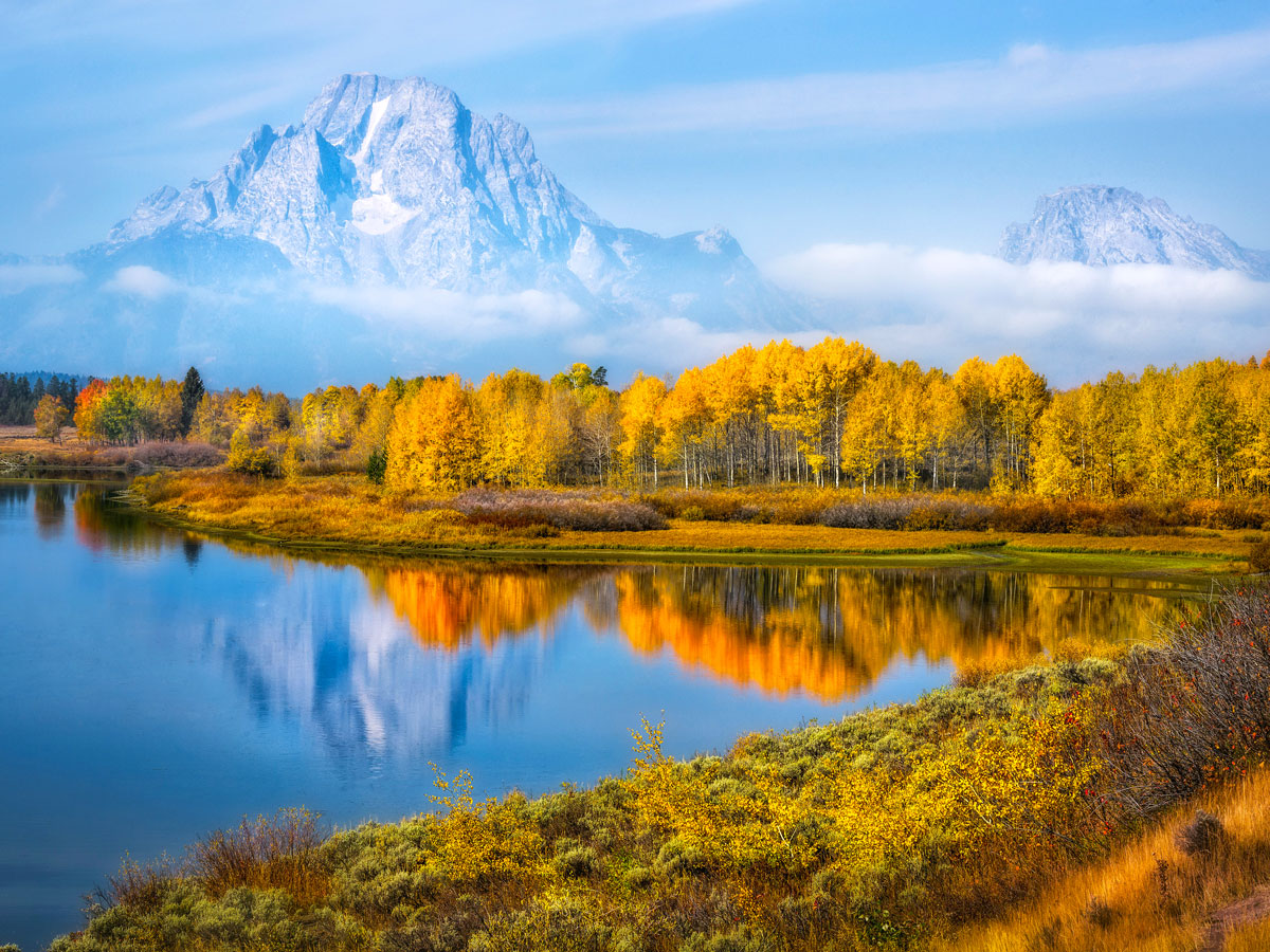 Trees in autumn reflecting on lake with mountains in background in Jackson Hole, Wyoming