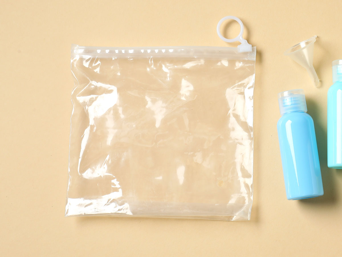 Clear plastic bag and small reusable toiletry bottle on table