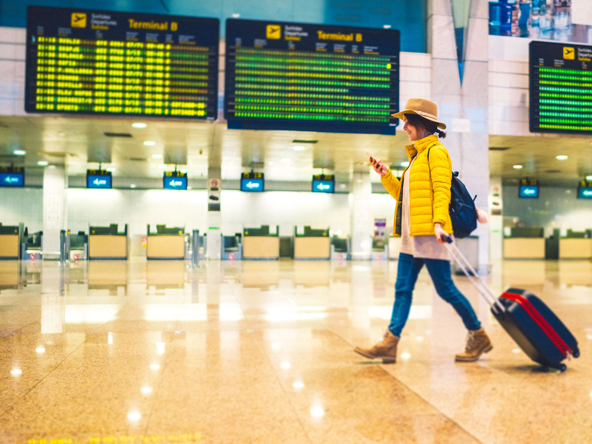 Traveler walking past departures board at airport