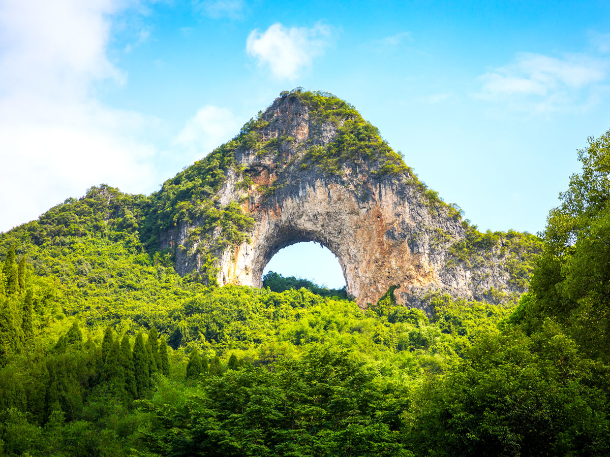 Qingxudong Arch rising above forest in China's Guizhou province