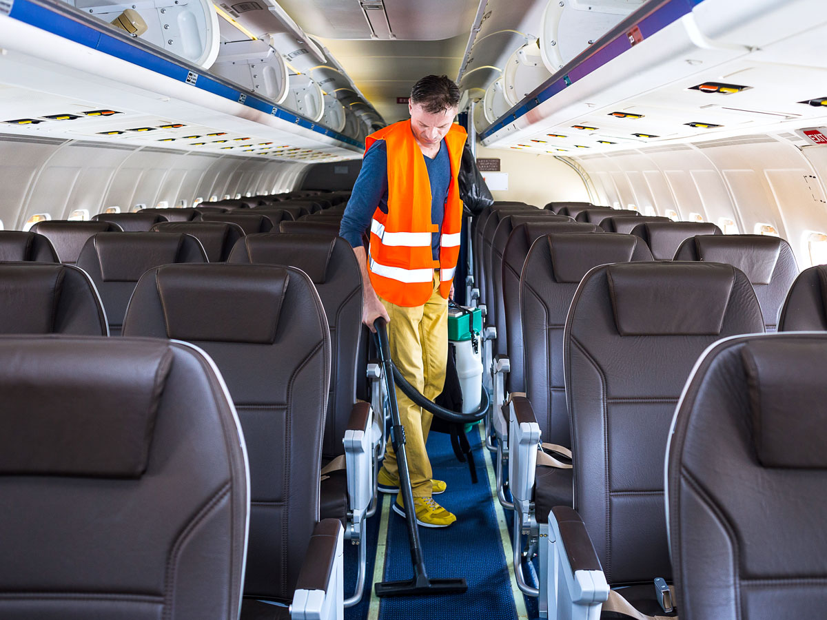 Cleaning crew vacuuming floor of aircraft cabin