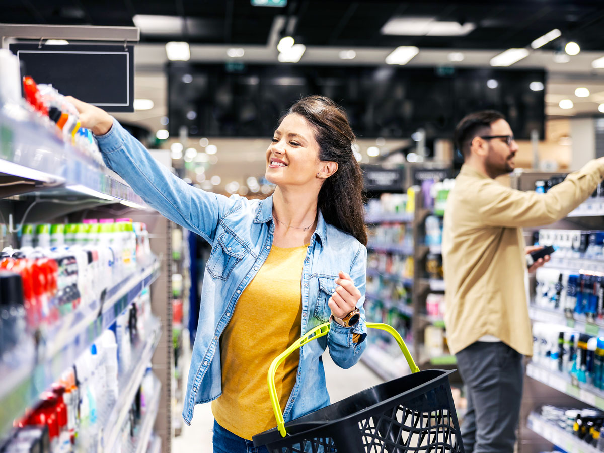 Shopper reaching for toiletries in store aisle