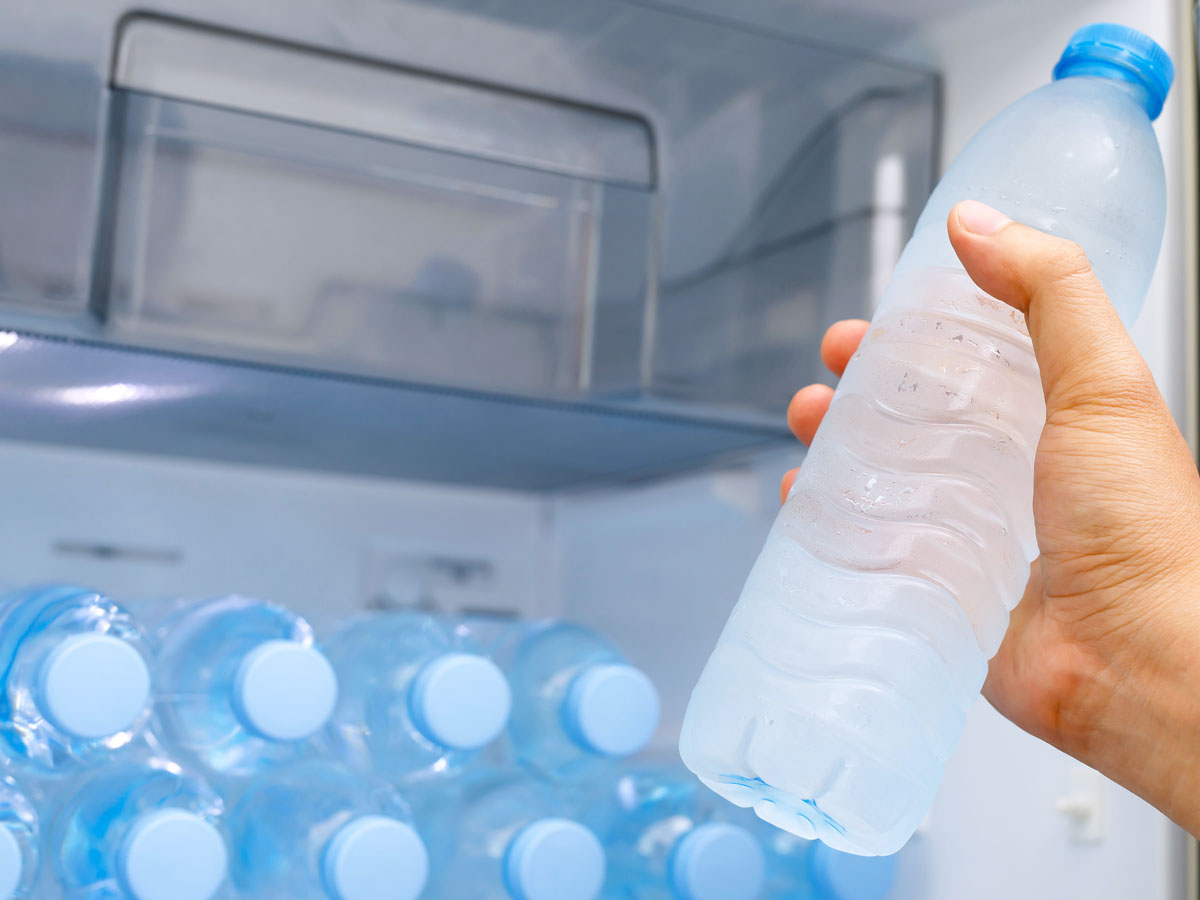 Person taking water bottle from fridge