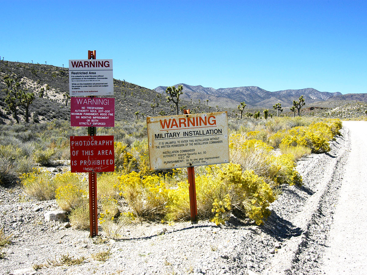 Signs posted on side of desert road warning of restricted military area