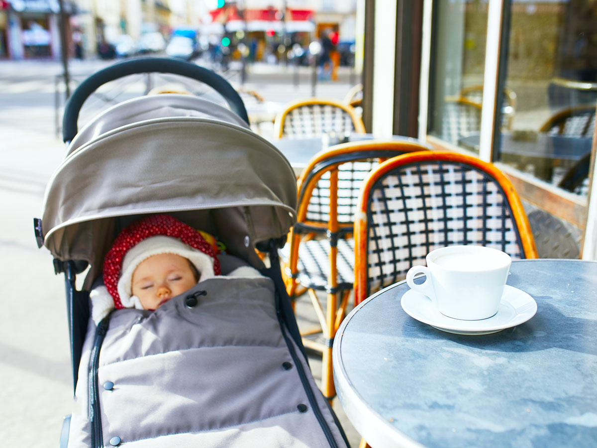 Baby in stroller next to cafe table outdoors