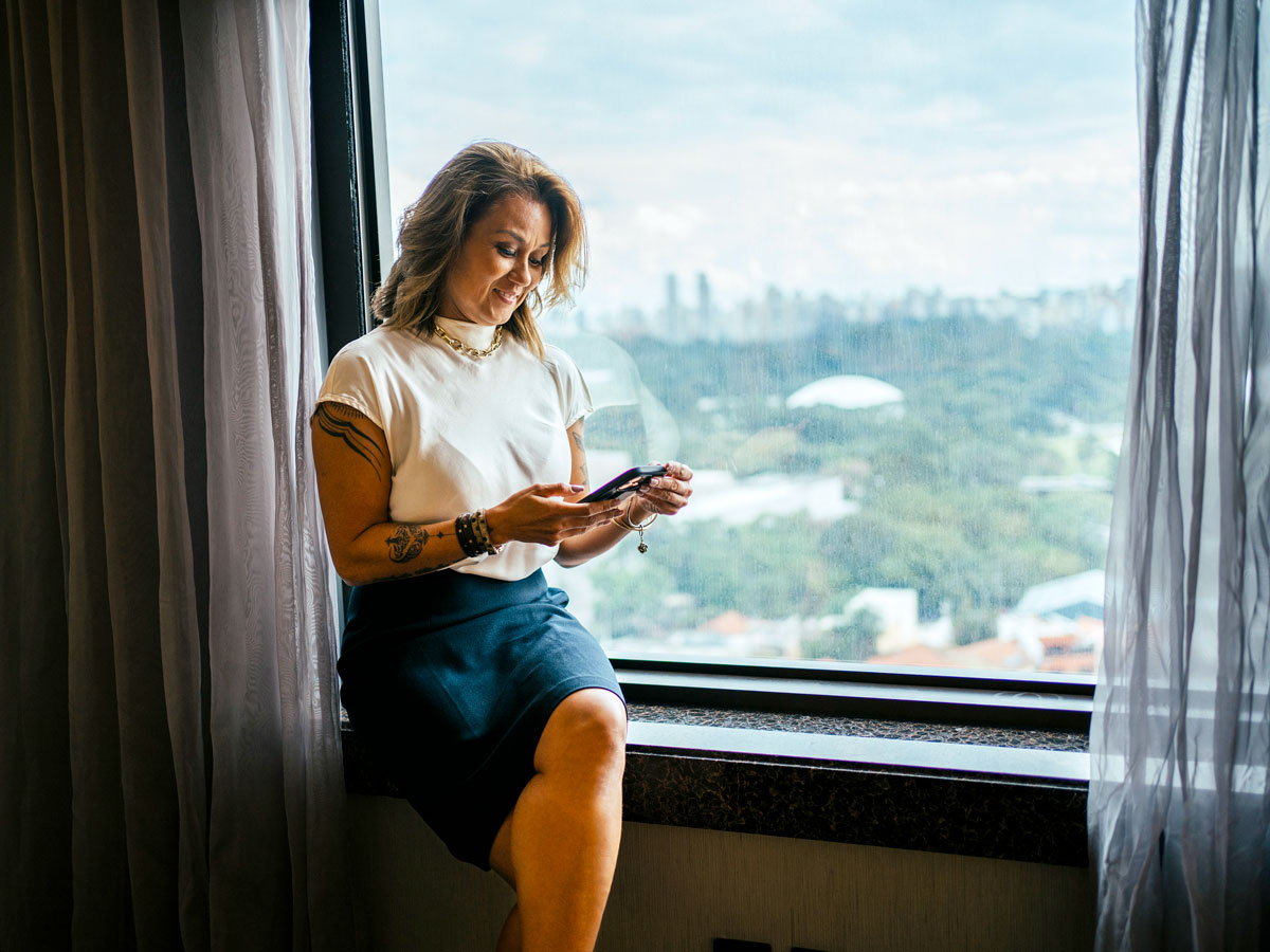 Hotel guest leaning on window and looking at her cellphone