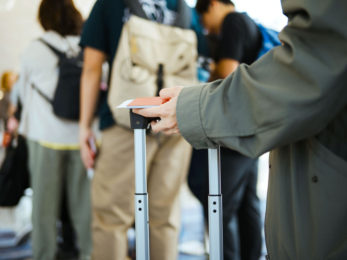 Traveler resting boarding pass and passport on luggage handle