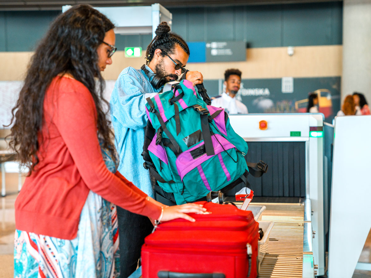 Passengers placing bags on belt for X-ray screening