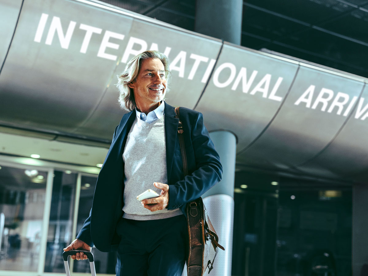 Man standing beside sign for international arrivals in airport terminal