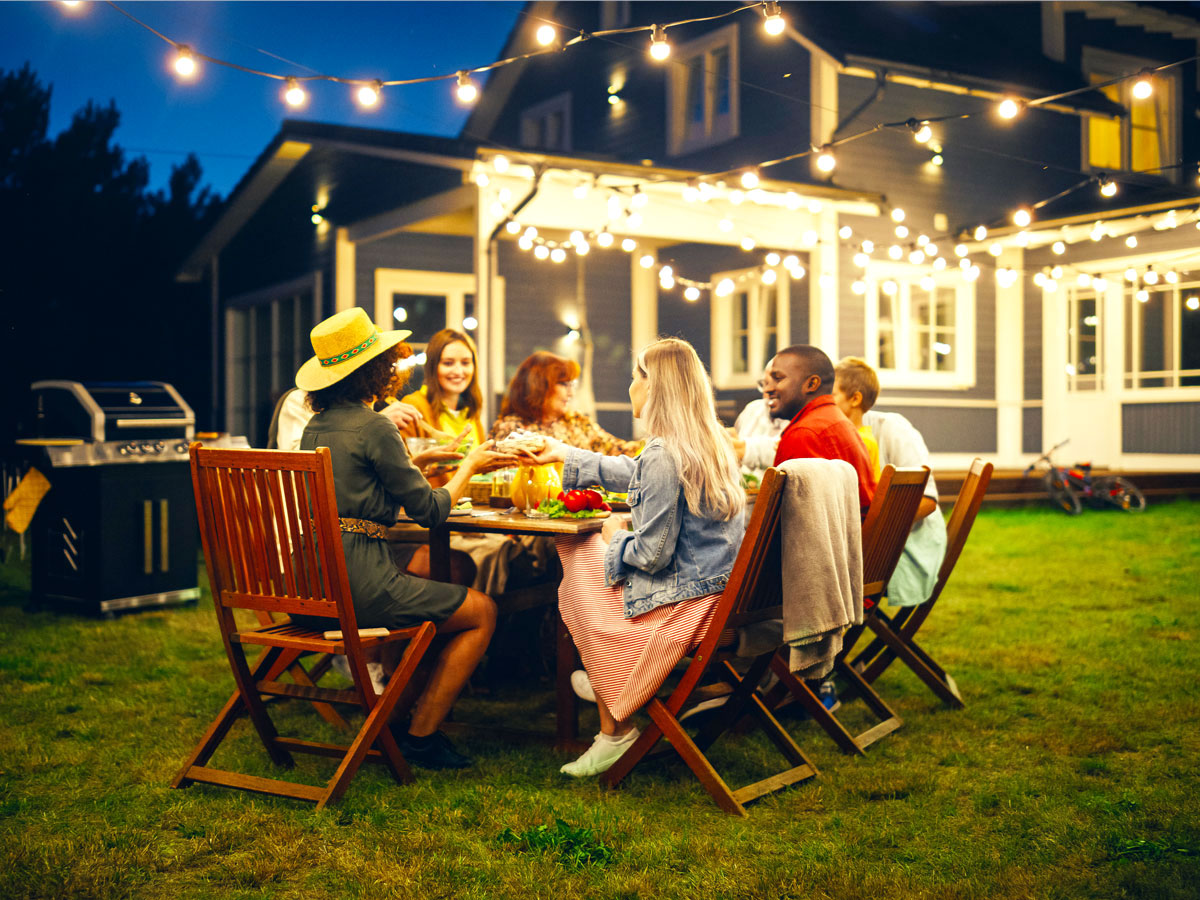Group eating dinner outside under hanging lights