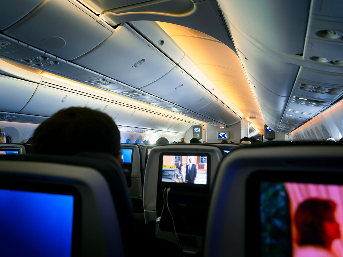 Passengers watching entertainment screens in dim airplane cabin