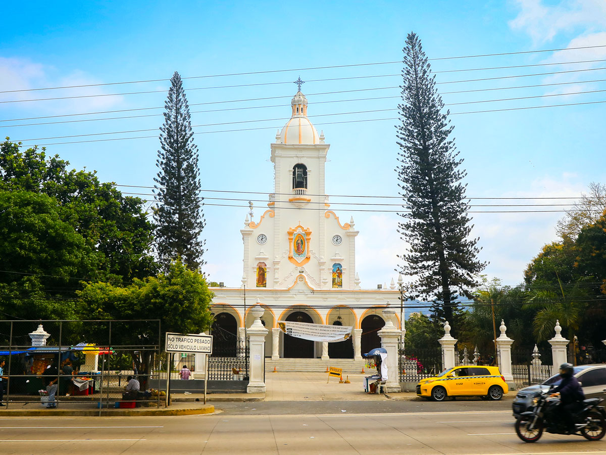 Yellow taxi outside historic church in San Salvador, El Salvador