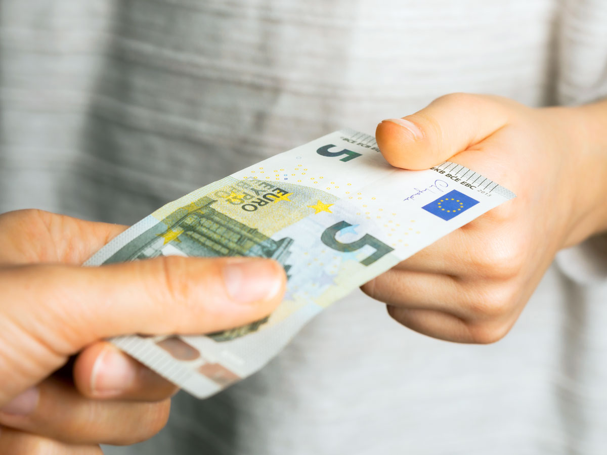 Two people exchanging a five-pound note