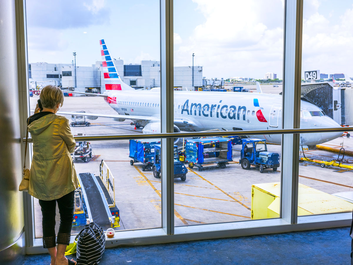 Passenger looking out terminal window at American Airlines Boeing 737 parked at gate