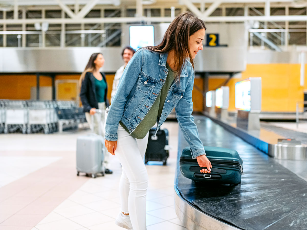 Passenger retrieving suitcase from baggage carousel