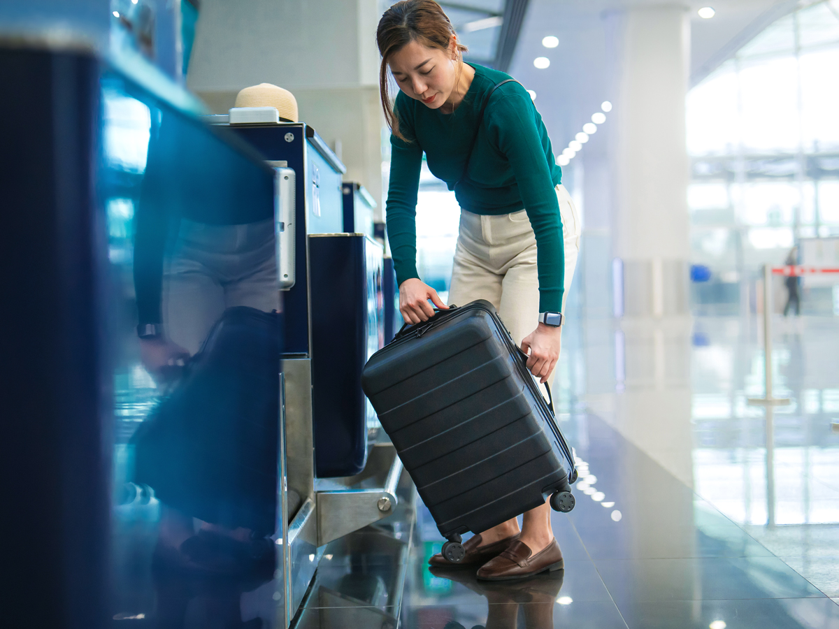 Passenger lifting bag onto scale at airport check-in counter