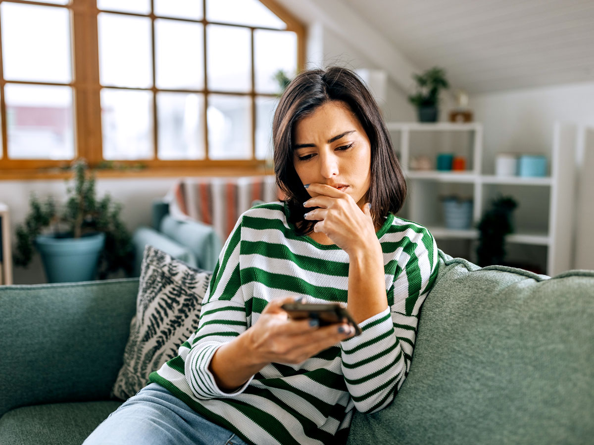 Woman sitting on couch using phone
