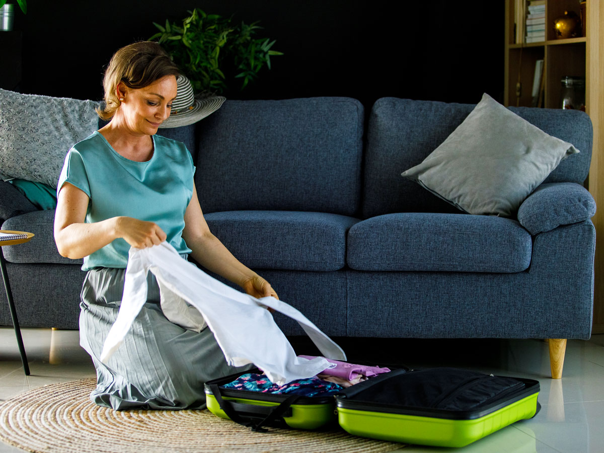 Person kneeling on ground and packing suitcase