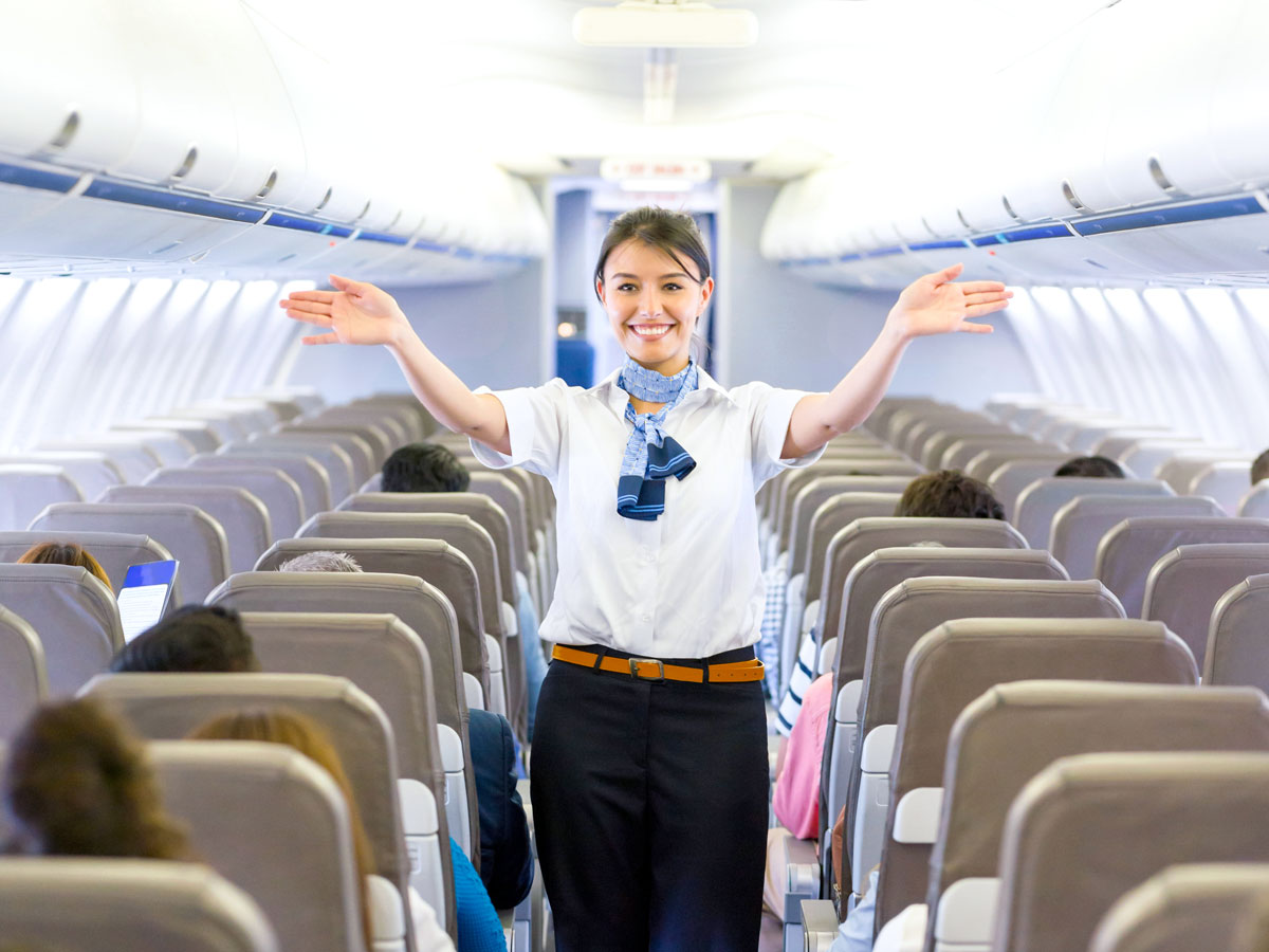 Flight attendant performing safety demonstration in aircraft aisle
