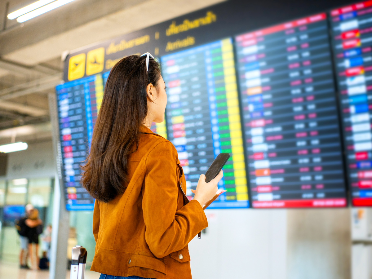 Traveler looking at departures and arrivals screen in airport