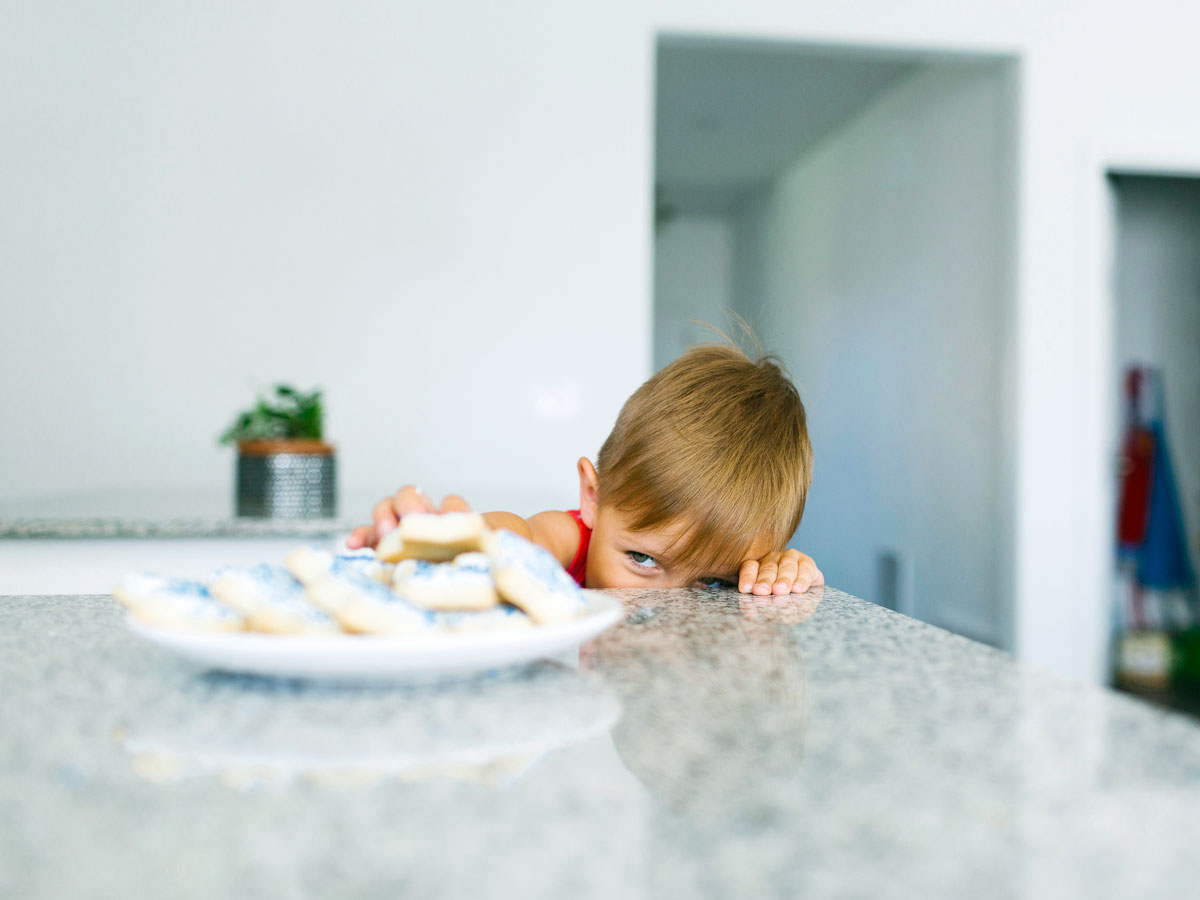 A cheeky British child sneaking a biscuit from the counter
